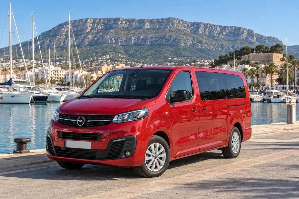 Furgoneta Opel Vivaro roja de 9 plazas de alquiler junto al puerto de Denia, con el Montgó al fondo